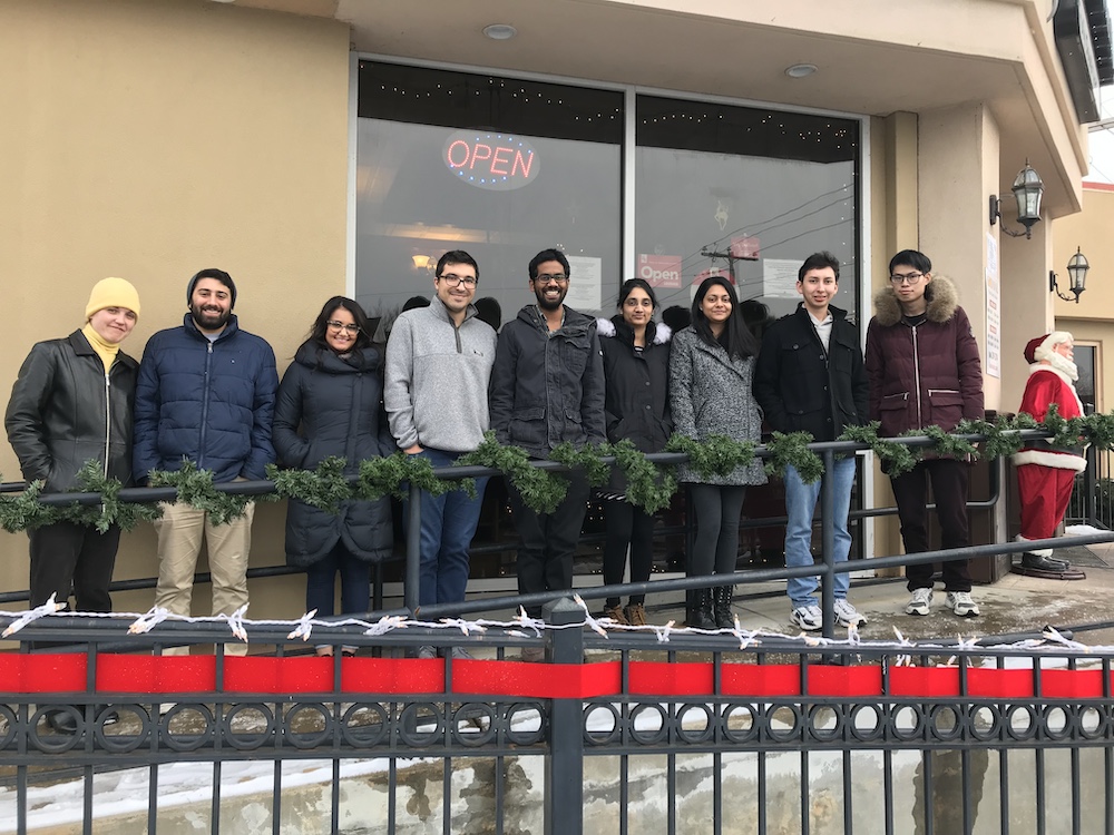 CMCD group members with spouses standing outside in front of a restaurant window.