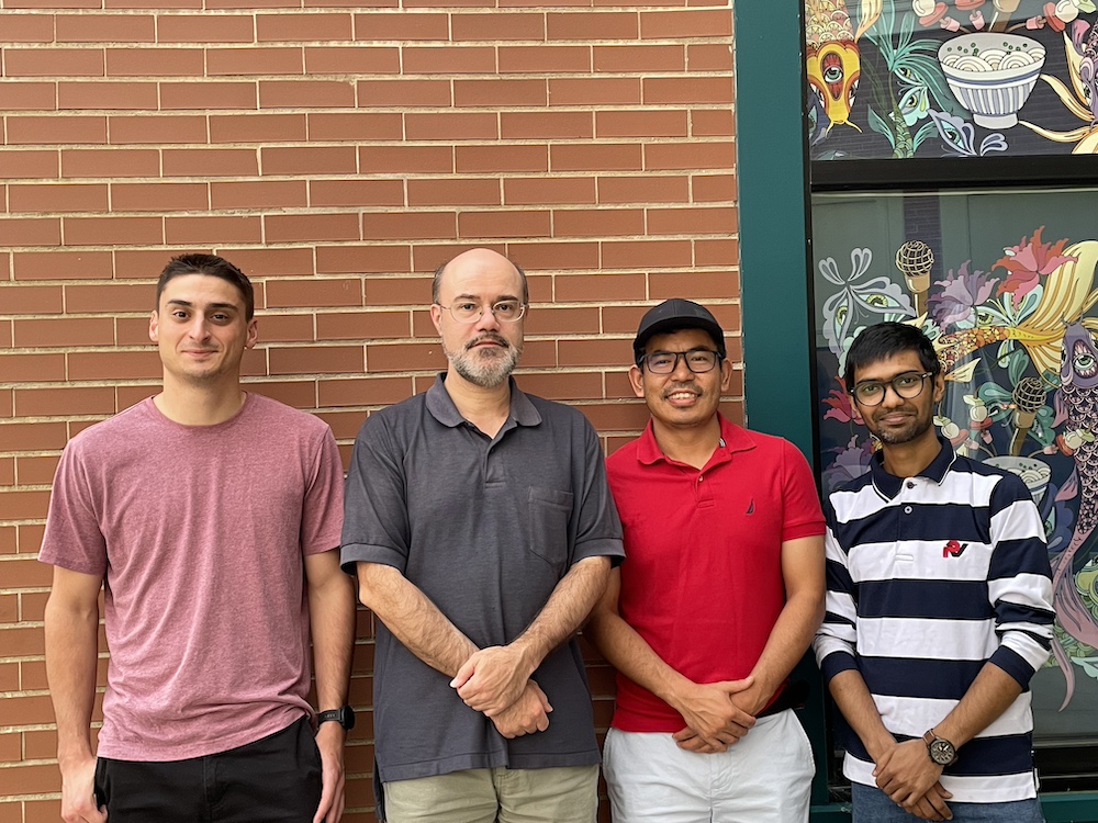 CMCD group members standing against a brick wall background.